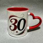 White mug with red interior and a heart-shaped red handle, featuring a large decorative '30' and swirls.