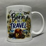 Mug with a travel-themed collage: globe, palm trees, luggage, camera, and the phrase “Born to Travel.”