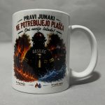 White ceramic mug featuring a fiery graphic with flames and smoke and partial red/black text around the top edge; photographed from the side on a gray surface.